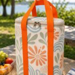 original coastal print insulated lunch tote bag with orange handles in a sunny picnic setting