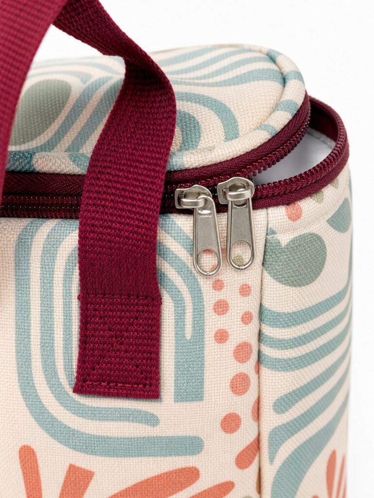 close up of burgundy zipper handle stitching padded piping and sea glass geometric printed canvas