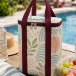 sea glass geometric insulated cooler tote bag with burgundy handles in a sunny poolside picnic setting