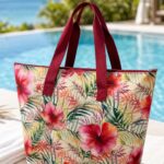 tropical floral beach tote bag with burgundy handles in a sunny poolside resort setting