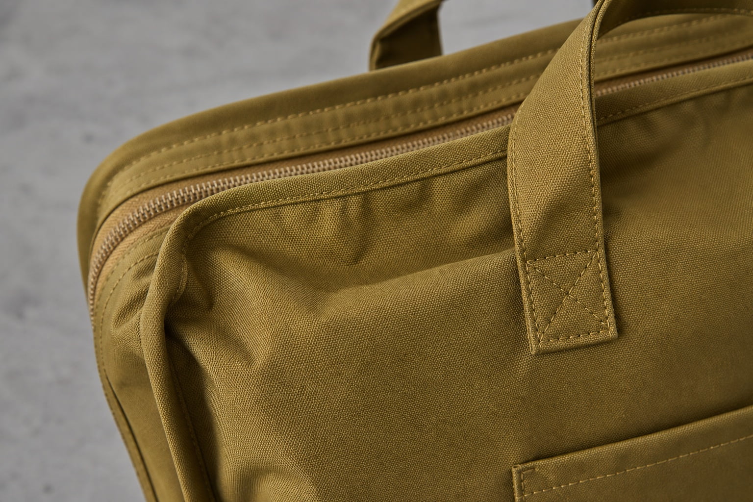 Close view of mustard travel bag handle zipper and reinforced stitching